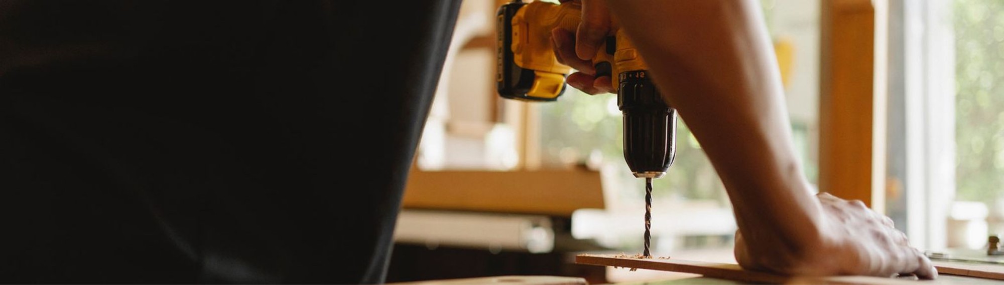 carpenter drilling a hole in a wood plank